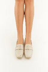 Mocasines de cuero vacuno color beige con textura efecto cocodrilo, punta cuadrada y taco bajo.
