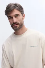 Remera de manga corta color gris oscuro con cuello redondo y calce regular. Presenta un estampado artístico rectangular en la espalda con diseño de manchas en tonos azules y texto descriptivo.