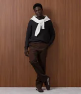 Pantalón slim de sarga lavada color marrón, con cierre de botón y cremallera, trabillas para cinturón y bolsillos laterales y traseros.