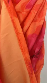 Vestido corto de microtul con diseño drapeado, escote strapless y estampado floral en tonos naranja y fucsia.