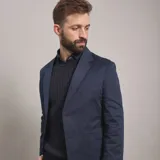 Saco de gabardina azul marino con solapa de muesca, dos botones frontales y bolsillos de parche.