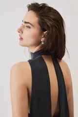 Blusa crop azul oscuro con cuello alto y diseño sin mangas, de tela con caída suave y ligero brillo.