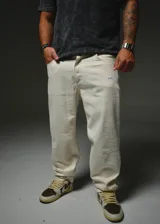 Pantalón de denim blanco de corte recto y holgado, con bolsillos laterales y pequeños detalles de etiquetas bordadas de la marca.