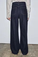 Jeans de tiro alto con corte wide leg y largo completo. Presenta diseño de cinco bolsillos, trabillas en la cintura y cierre frontal con cremallera y botón, con un acabado de efecto lavado.