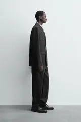 Blazer de corte regular confeccionada en tejido de lana italiana. Presenta cuello con solapas de pico, cierre frontal de botonadura cruzada, manga larga con puños abotonados, bolsillos de vivo en el pecho y bolsillos de solapa en la cadera.