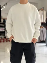 Buzo oversize de corte amplio, color blanco, con cuello redondo y puños y dobladillo en rib elástico.