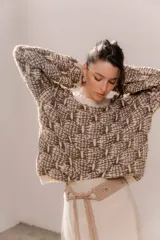 Buzo de tejido grueso con diseño artesanal bicolor en tonos marrón y crema. Presenta cuello redondo y terminaciones en rib en puños y cintura, con un calce relajado.