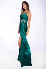 Vestido largo de satén color verde esmeralda, con breteles finos y escote drapeado. Presenta un lazo con apliques de strass en la cintura y tajo en la falda.