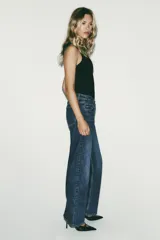 Body negro de escote asimétrico y manga sisa. Presenta un drapeado en el delantero y cierre inferior con botones a presión.