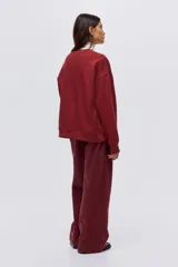 Buzo de cuello redondo con hombros caídos y diseño estampado con texto en el frente. Presenta puños y bajo acanalados.