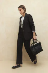 Pantalón negro de vestir, de tiro alto y corte ancho, con bolsillos laterales y cintura elástica.