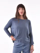 Remera de manga larga con cuello redondo, confeccionada en tejido de punto con textura jaspeada y acabado suave. Presenta un corte holgado y puños ajustados en las mangas.