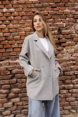 Tapado de paño color rosado, de corte oversized y diseño cruzado. Presenta solapas clásicas, mangas largas con puños vueltos y amplios bolsillos delanteros. Cierre frontal con un botón visible.