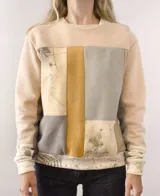 Buzo deportivo unisex color crema con estampado de hojas y manchas de colores.