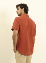 Camisa sport de manga corta, confeccionada en una mezcla de lino y algodón. Presenta cuello clásico, cierre frontal con botones de coco y un bolsillo aplicado en el pecho.