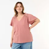 Camiseta rosada de manga corta con escote en V, confeccionada en tejido texturizado con detalles de encaje y macramé en los hombros.