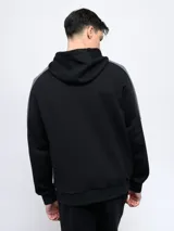 Canguro negro con capucha, corte clásico, mangas largas con franjas grises y logo de la marca bordado en el pecho.