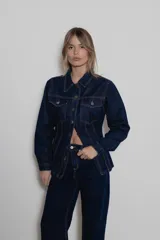 Chaqueta de denim de algodón con corte entallado en la cintura, cuello clásico, cierre frontal con botones metálicos y dos bolsillos con solapa en el pecho.