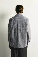 Camisa de corte regular fit confeccionada en tejido fluido con viscosa. Presenta cuello bowling, manga larga con puños abotonados y cierre frontal con botones.
