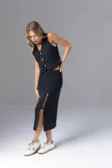 Falda midi negra con finas rayas verticales blancas, corte recto y abertura lateral con cordones cruzados.