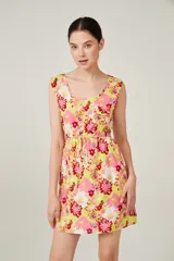 Vestido corto con estampado floral en tonos amarillo, rosa y rojo, con escote redondo, sin mangas y cintura elastizada con lazo.