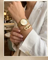 Pulsera de acero con baño de oro, compuesta por una cadena de eslabones finos y un dije central de eslabones ovalados entrelazados.