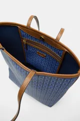 Bolso tipo tote de hombro con cuerpo estampado en tonos azules con patrón geométrico. Cuenta con detalles en tono tostado en las asas dobles, bordes y costuras en contraste. Cierre mediante botón imantado y compartimento interior.