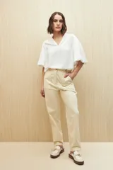 Pantalón color beige de tiro alto y corte recto, con bolsillos delanteros amplios con botones.