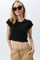 Top corto de manga corta, color negro con efecto desgastado o acid wash, cuello redondo y costuras verticales que definen la silueta.