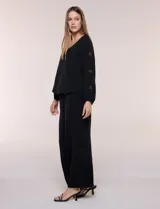 Blusa azul de corte holgado y fluido, con escote en V y mangas largas raglán que presentan detalles de calados con forma de flores y puños elastizados.