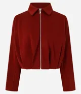 Campera corta estilo baloné en algodón con felpa de color bordó, con cuello camisero, cierre frontal de cremallera metálica y mangas largas.