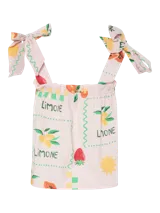 Top corto sin mangas con cuello cuadrado y tirantes ajustables con lazo. Presenta un estampado de frutas (fresas, limones/naranjas) y un patrón de cuadros en tonos verde, amarillo y rosa pálido. El borde del escote y el ruedo tienen un ribete ondulado verde.