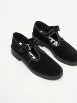 Zapatos tipo guillermina de gamuza color bordó, con diseño de tira en T, cierre con hebilla metálica y costuras a la vista en hilo blanco. Poseen una suela de plataforma de goma negra de 4 cm.