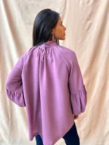 Blusa verde con cuello alto fruncido y mangas largas abullonadas.