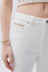 Jean blanco de tiro medio-alto y pierna acampanada estilo Oxford, con pespuntes en zigzag en los bolsillos traseros y terminación desflecada.