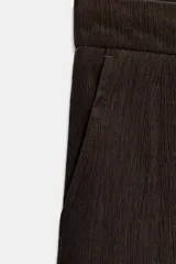 Pantalón bombacho de tiro alto, color marrón, con efecto arrugado y cintura elástica en la espalda. Cuenta con pinzas delanteras, bolsillos frontales, pernera abullonada y puños acabados en lazo.