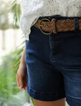 Short de jean azul oscuro, con pretina con pasadores, botón y cierre. Delantera con bolsillos. Botón en bolsillos traseros. Incluye cinturón trenzado marrón con hebilla redonda dorada.