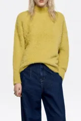 Jersey de textura suave y peluda, con cuello subido y manga larga, diseñado con un corte cómodo y envolvente.