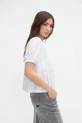 Blusa negra de broderie con mangas cortas abullonadas, cuello redondo y calce clásico.