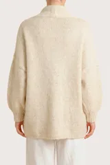 Saco abierto de punto en color beige, con diseño de manga larga y puños acanalados. Presenta un tejido con sutiles destellos brillantes integrados.