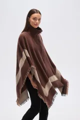 Poncho de color marrón con diseño geométrico en beige. Presenta un cuello alto de punto acanalado con cierre frontal parcial y bordes con terminaciones desflecadas.