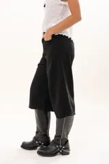 Bermuda de corte amplio y tiro alto en color negro, con cierre frontal de botón y bolsillos laterales.