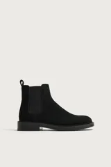 Bota chelsea de cuero con acabado de serraje color negro, con elásticos laterales y tira trasera para facilitar el calce.