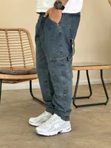 Pantalón tipo carpenter de denim azul con corte holgado, bolsillos laterales utilitarios y cierre frontal con botón.