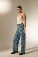 Pantalon de jean de corte recto con estampado floral en tonos claros sobre base azul. Presenta bolsillos funcionales y tiro medio.