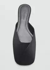 Zapato destalonado plano de color negro con punta redonda, confeccionado con corte de poliéster y suela de caucho.