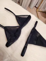 Conjunto de lencería compuesto por un corpiño triangular de microtul transparente con detalles de encaje en las copas y una tanga regulable de elástico ancho.