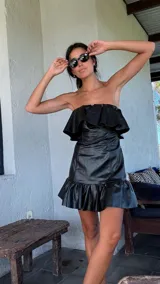 Vestido corto de cuero sintético color verde claro, con escote strapless y detalle de volados en el pecho y en el ruedo.