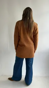 Abrigo estilo sastrero de textura tipo bouclé en color camel, con cierre frontal de un botón, solapas clásicas y bolsillos frontales tipo plaqué.