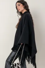 Ruana de lana color beige, tejida en punto acanalado con terminación de flecos en los bordes.